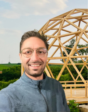 Anton Kozak in prim plan, in plan secundar o structura geodezica de tip dome